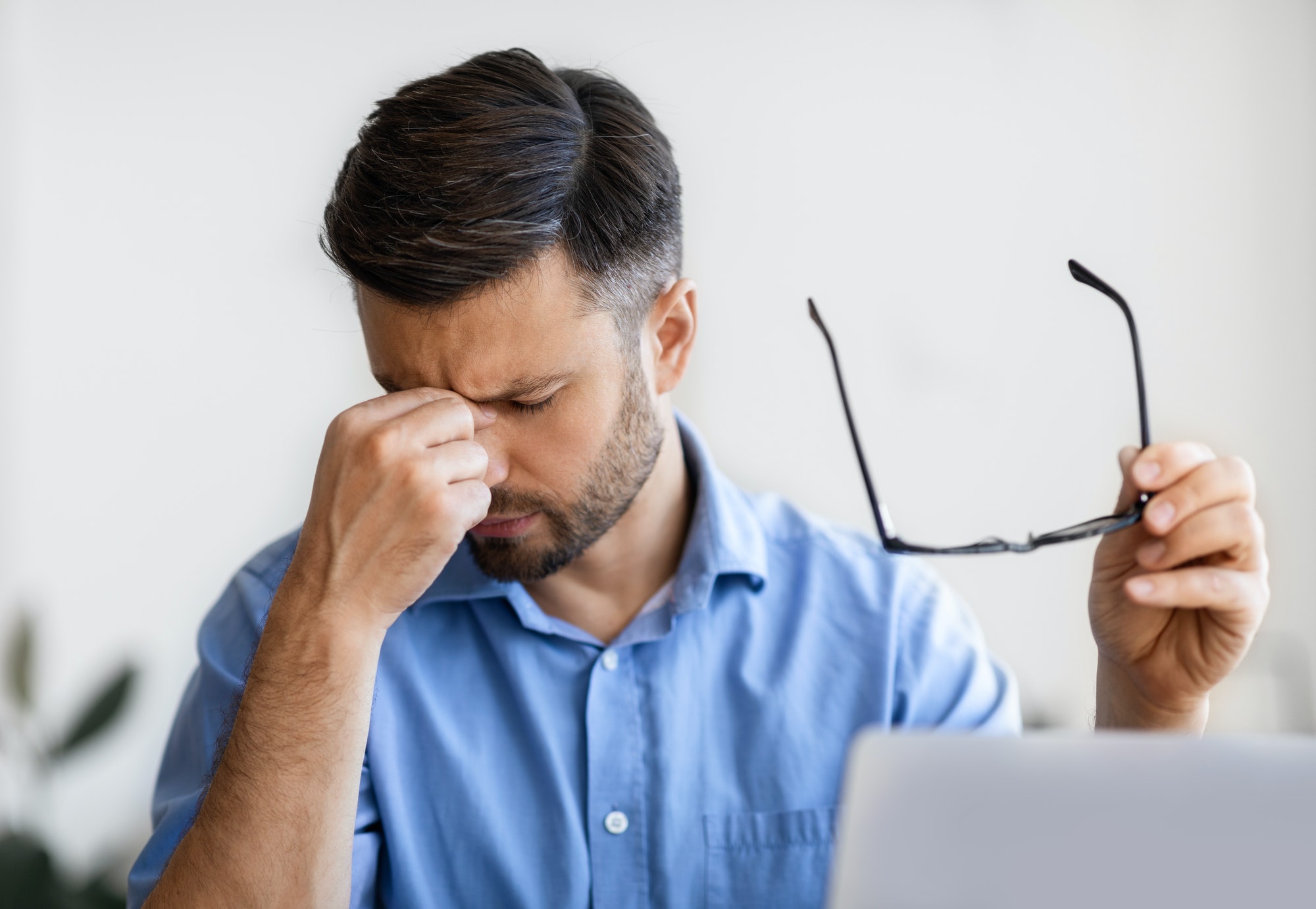 Eyes Pain. Millennial businessman massaging nosebridge, tired after working on laptop computer